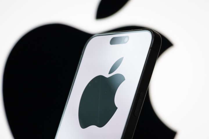 Apple logo displayed on a smartphone screen with stock market graphs in background